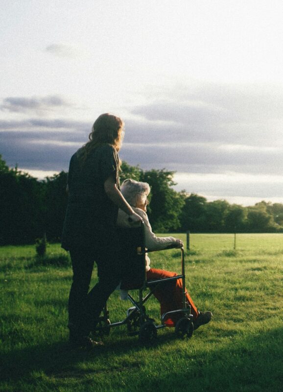 Pushing an elderly woman in a wheelchair in a meadow