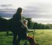 Pushing an elderly woman in a wheelchair in a meadow